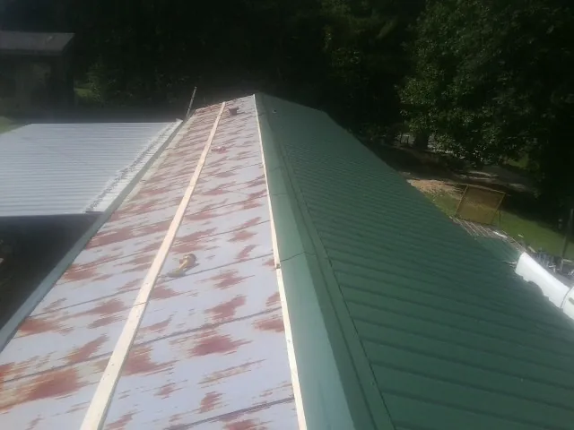 Old rusted panels beside newly installed green metal roofing — Wind Damage Roof Repair by Roofing Brothers in Chula