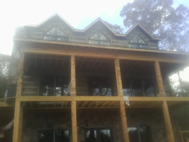 Dormers and porch framing on a large log home under construction — Roof Coating work by our crew in Chula