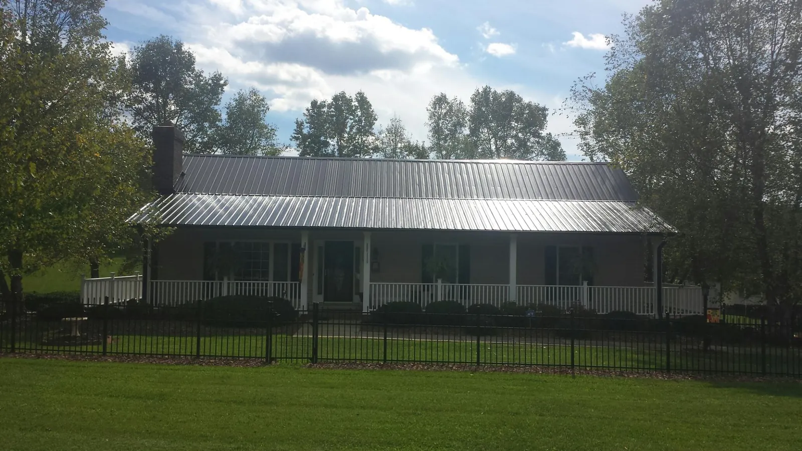 Gray metal roof on a brick ranch with a full width front porch — Gutter Guard Installation work by our crew in Chula