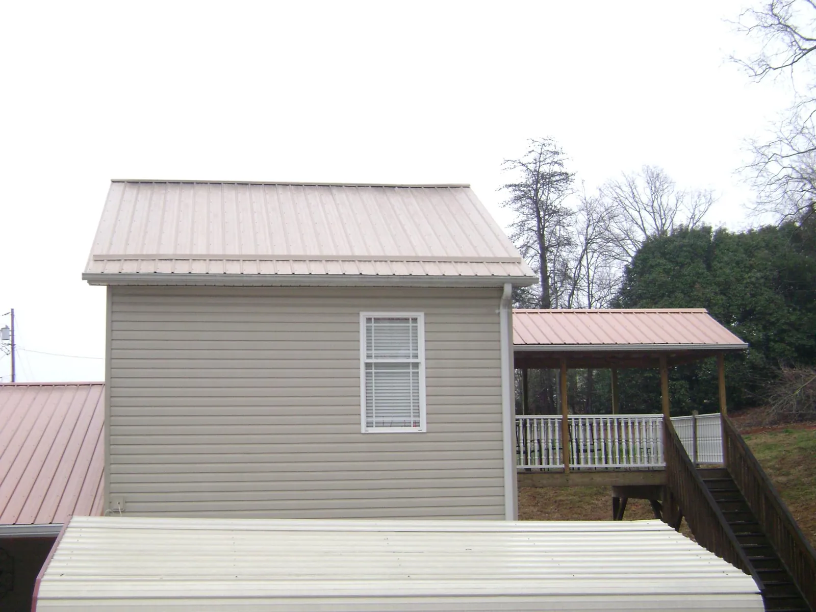Tan metal roofs on a two story addition and attached porch, from a Roof Replacement job in Chula