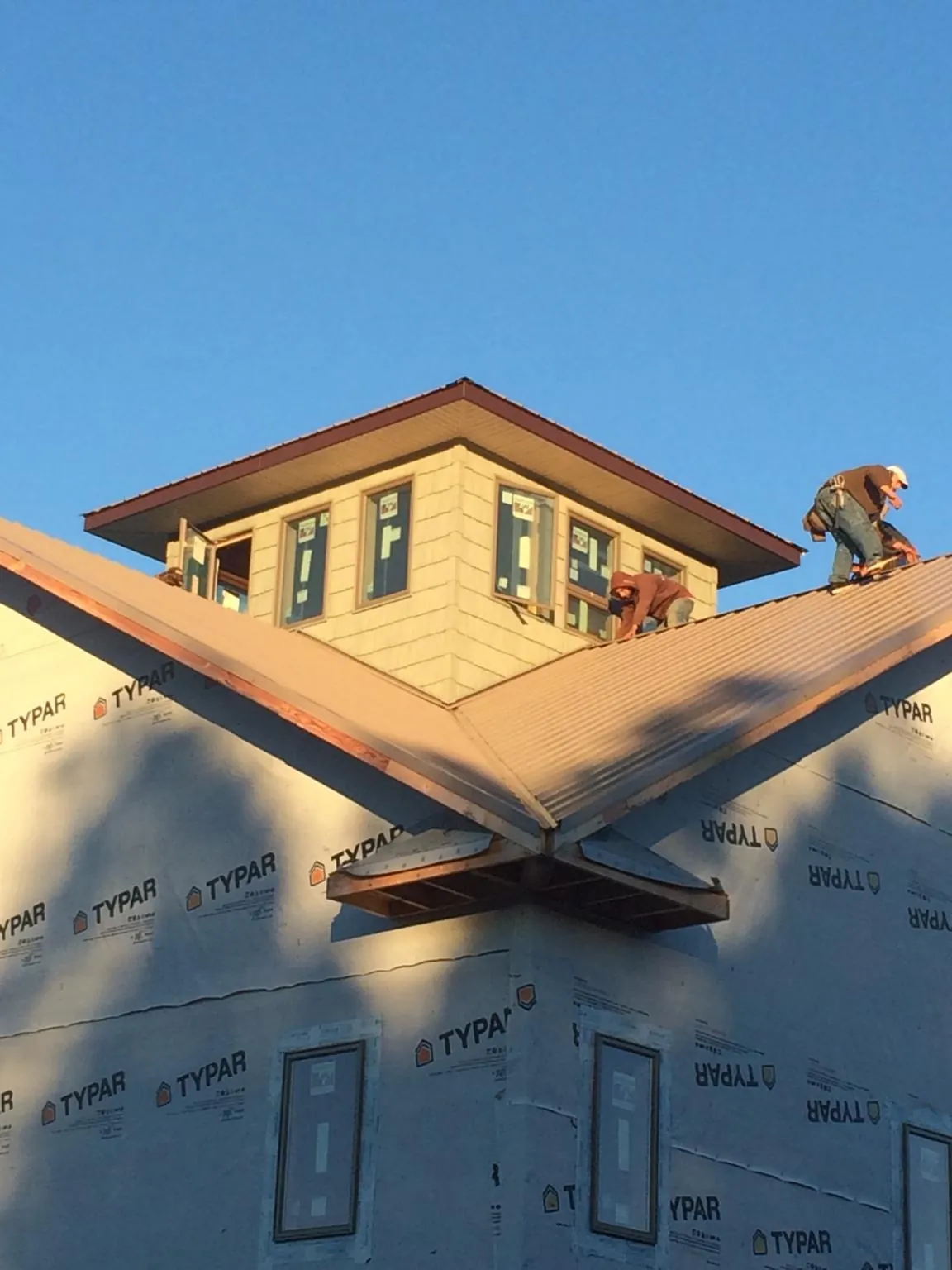Roofers working around a rooftop cupola on a new metal roof at sunset — Roof Waterproofing in Chula by Roofing Brothers